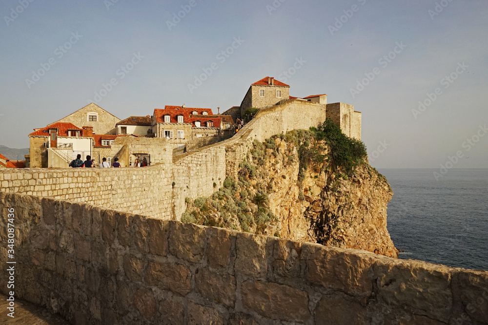 Exterior architecture and design of Dubrovnik old town city walls and landscape with clear blue sky, southern Croatia fronting the Adriatic sea encircled with massive stone Exterior architecture and design of Dubrovnik old town city walls and landscape with clear blue sky, southern Croatia fronting the Adriatic sea encircled with massive stone