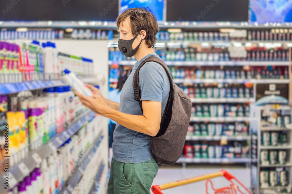 Alarmed man wears medical mask against coronavirus while purchase of household chemicals in supermarket or store- health, safety and pandemic concept - young woman wearing protective mask and