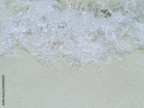 Waves running on white sand, close up view. Bubbling water. View from above.