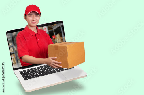 Asian delivery woman in red shirt with blur warehouse background, holding goods order in package parcel out from laptop computer isolated with copy space. order online and delivery service concept © asiandelight