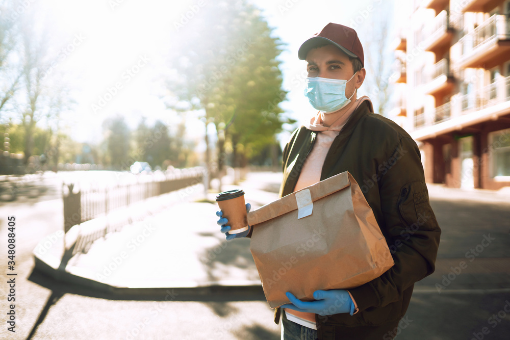 Сourier delivers a bag of food and coffe in quarantine city. Delivery service concept. Covid-2019.