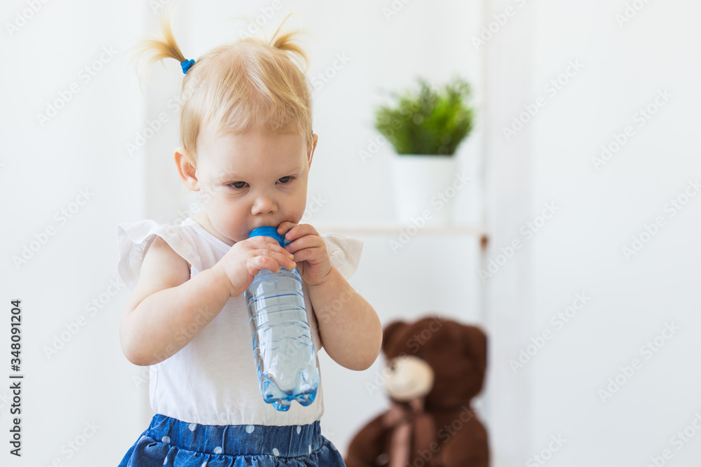 Hearing aid in baby girl's ear. Toddler child wearing a hearing aid at home. Disabled child, disability and deafness concept.