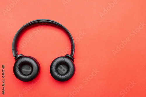 Black headphones on the left side of the photo. From above . Red background. Copy space