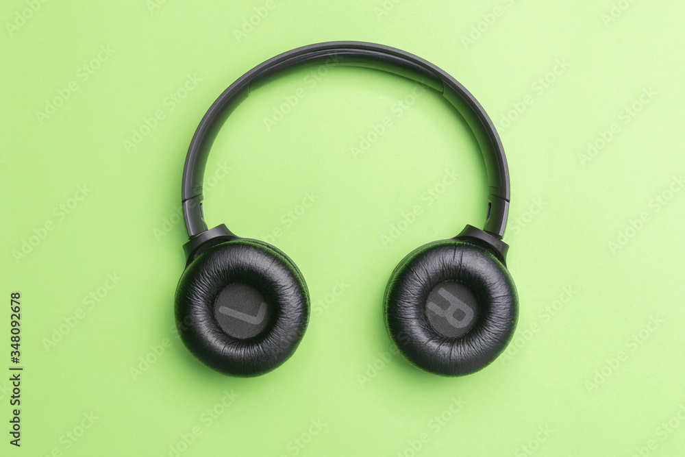 Black headphones oin the center of the photo. From above . Green background. Copy space Black headphones oin the center of the photo. From above . Green background. Copy space