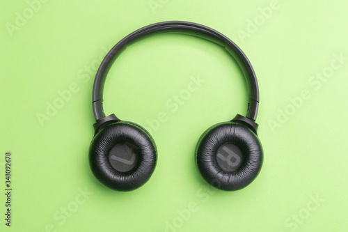 Black headphones oin the center of the photo. From above . Green background. Copy space