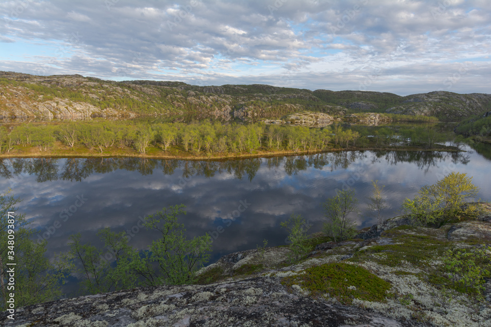 The reservoir is surrounded by hills and forest.Clouds are reflected in the water.Summer landscape.