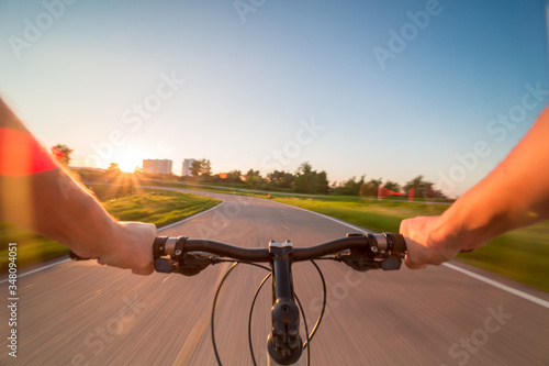 Hands holding handlebar of a bicycle with green meadow on background. View from bikers eyes. photo