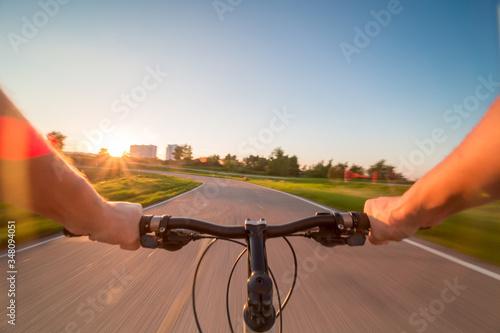 Фотография Hands holding handlebar of a bicycle with green meadow on background