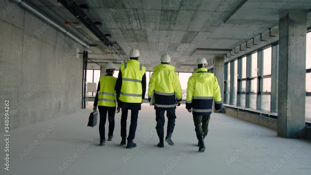 Rear view of group of engineers walking on construction site, talking.