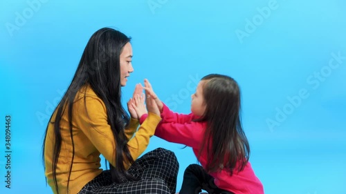 Happy young mommy and her cute kid daughter play patty cake and have fun together