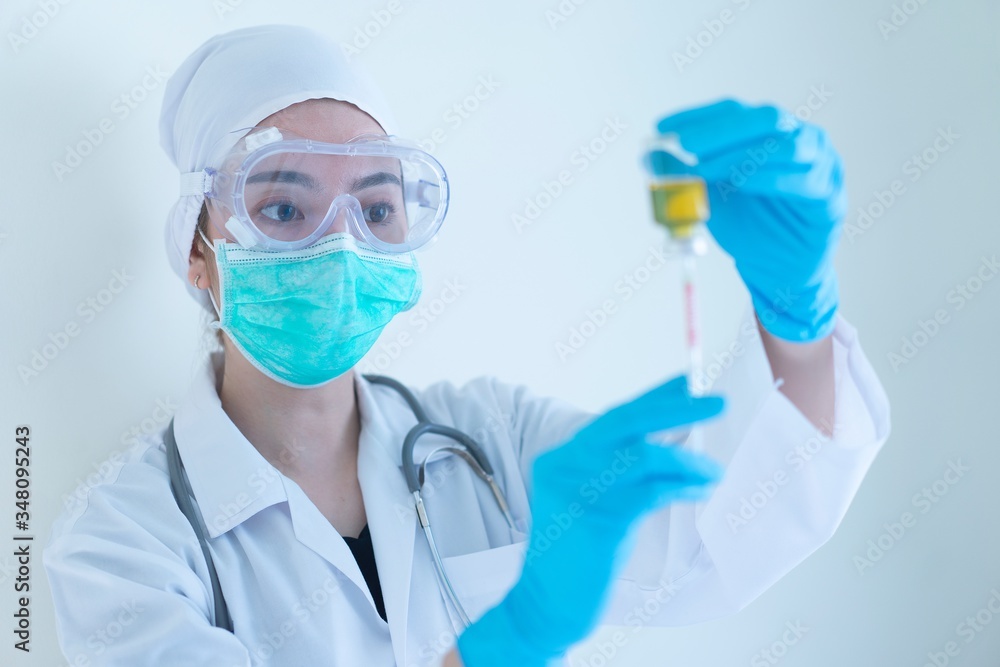 Biological hazard. Epidemic of the virus closeup female asian Doctors wearing protective clothing, Green mask and blue gloves holds an injection syringe and vaccine from, flu, coronavirus, covid-19 Biological hazard. Epidemic of the virus closeup female asian Doctors wearing protective clothing, Green mask and blue gloves holds an injection syringe and vaccine from, flu, coronavirus, covid-19