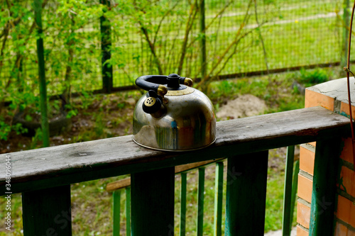 An old metal kettle stands on the railing of the veranda.