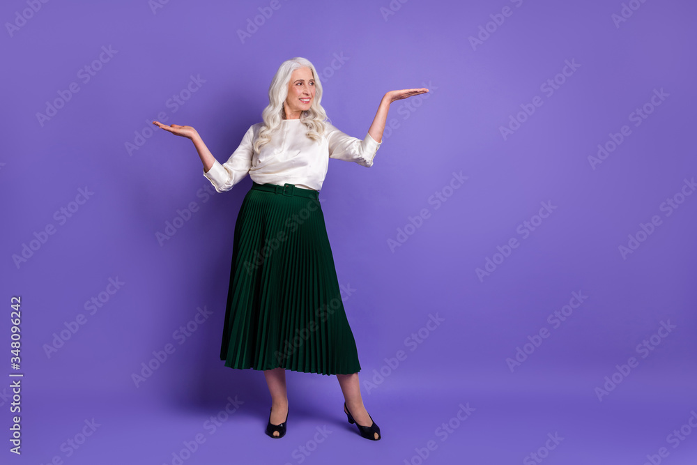 Naklejka premium Full length body size view of her she nice attractive chic lovely charming grey-haired woman holding copy space on palms isolated on bright vivid shine vibrant lilac violet purple color background