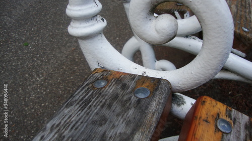 Closeup Of Nails On Wooden Park Bench with White, Rusty Handrails 