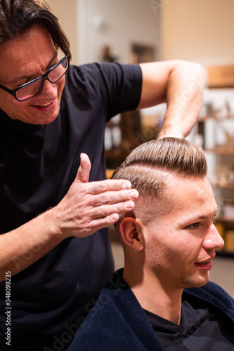 Φωτογραφία Barber rubs the hair of a young man with pomade