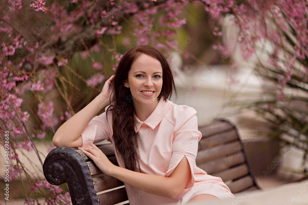 Portrait of a happy young woman 30-33 years old in nature in the park in spring. Flowering magnolia Portrait of a happy young woman 30-33 years old in nature in the park in spring. Flowering magnolia