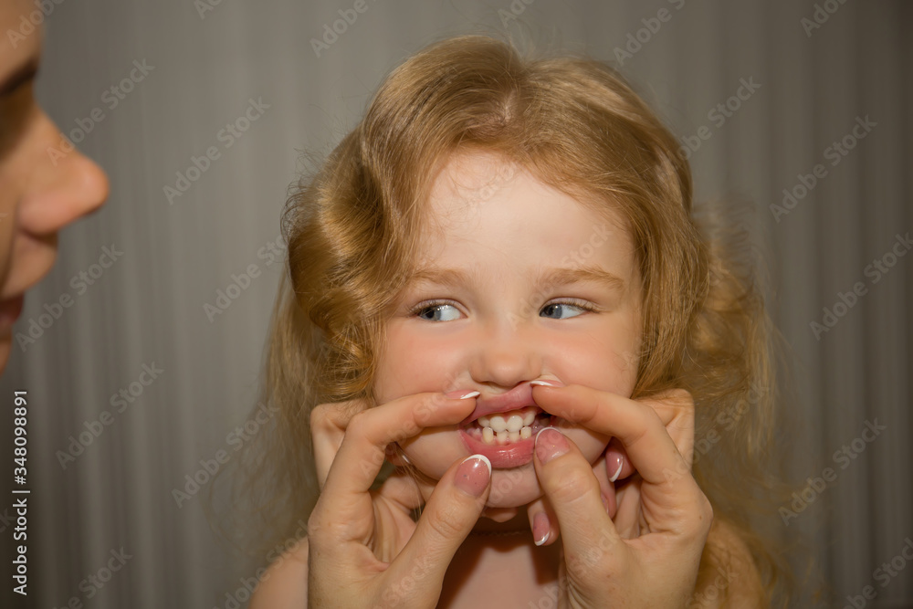 Little girl has blond hair, blue eyes, shows her teeth Little girl has blond hair, blue eyes, shows her teeth
