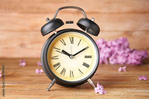 Alarm clock and flowers on wooden table. Spring time photo