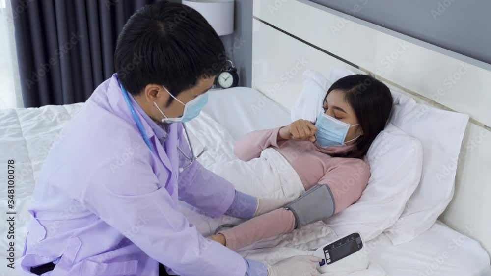 doctor measuring blood pressure of sick woman in bed, people must be wearing medical mask protecting from coronavirus(covid-19) pandemic doctor measuring blood pressure of sick woman in bed, people must be wearing medical mask protecting from coronavirus(covid-19) pandemic