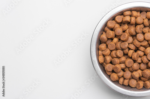 Dog food in a silver bowl. Half of the bowl on the right. White background. Copy, text sapce.