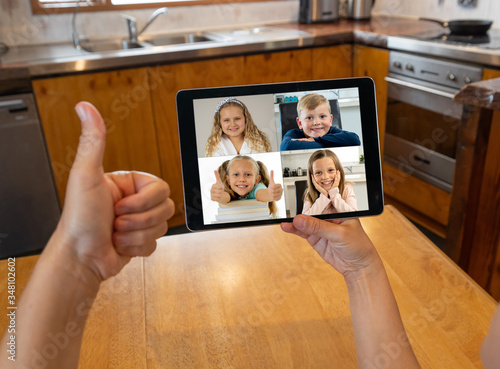Screen tablet image of school children learning online lesson listening to teacher