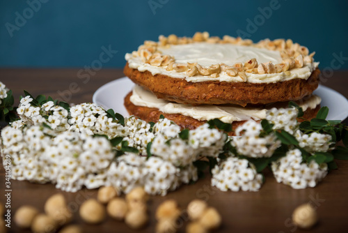 Carrot cake  branch with white flowers and hazel nuts on the wooden table