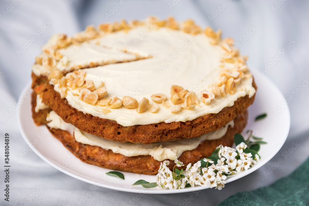 Carrot cake with hazel nuts, decorated with white flowers of meadowsweet and slice lemon on the white tablecloth Carrot cake with hazel nuts, decorated with white flowers of meadowsweet and slice lemon on the white tablecloth