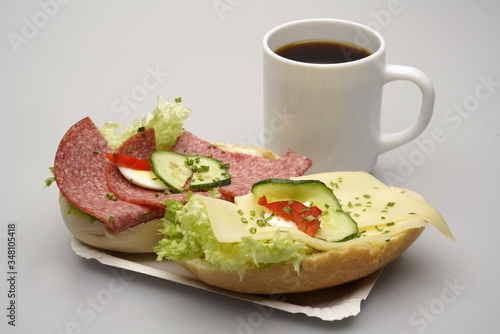 Obraz na płótnie Zwei halbe Belegte Brötchen mit Salami und Käse, Tasse Kaffee w salonie