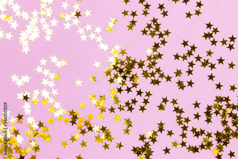 Golden stars confetti texture on a purple pastel background. Festive shiny backdrop.