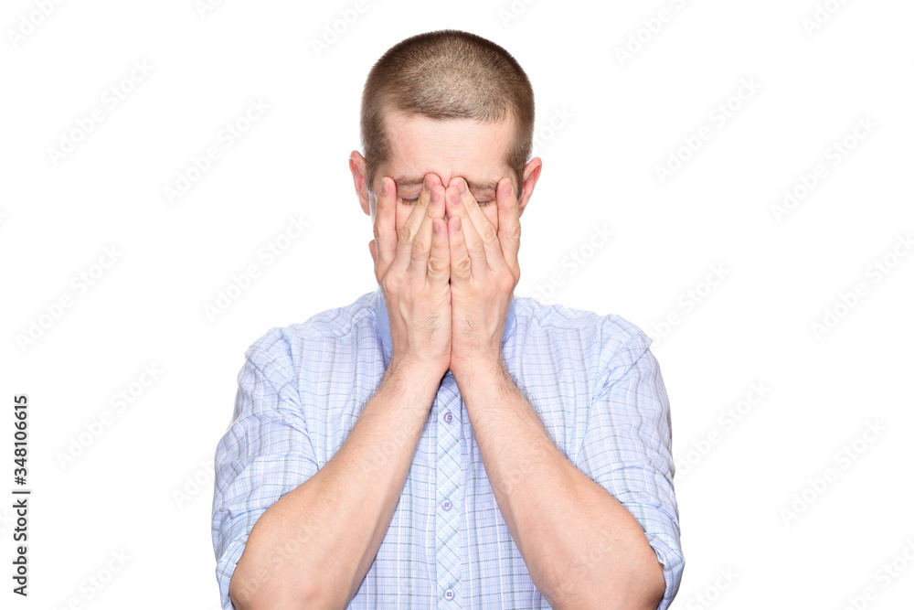 tired distressed man in a classic blue shirt, short haircut; closed his eyes with his hands, from a headache; Full-face. Isolated tired distressed man in a classic blue shirt, short haircut; closed his eyes with his hands, from a headache; Full-face. Isolated