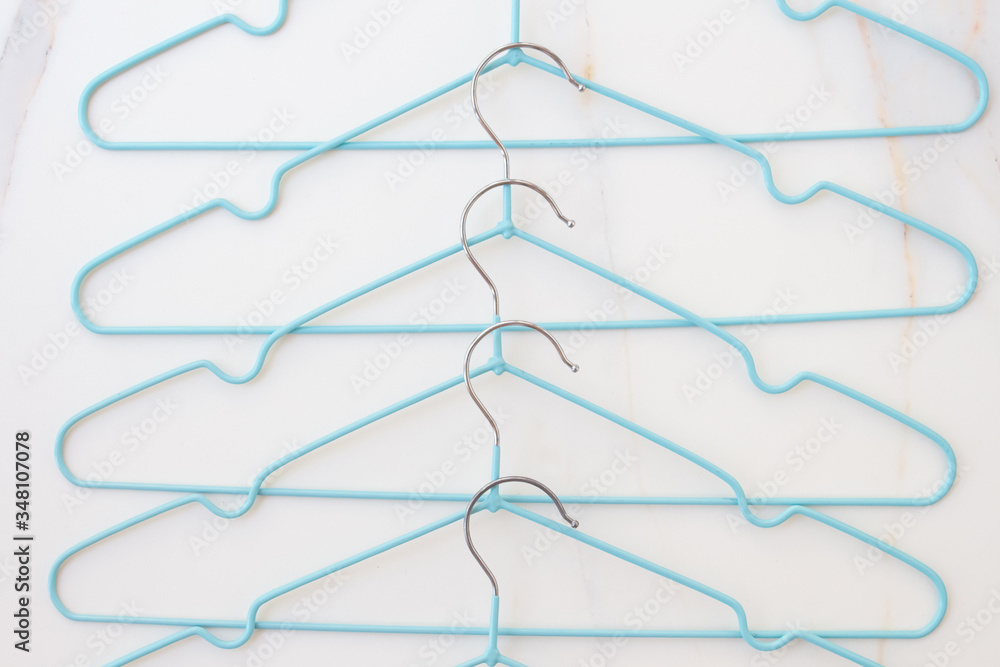 Fototapeta Modern blue hangers on white marble. Fashion blogger concept updating wardrobe for summer season. Minimalism