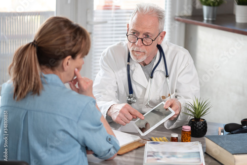 Doctor showing reports on digital tablet to his female patient