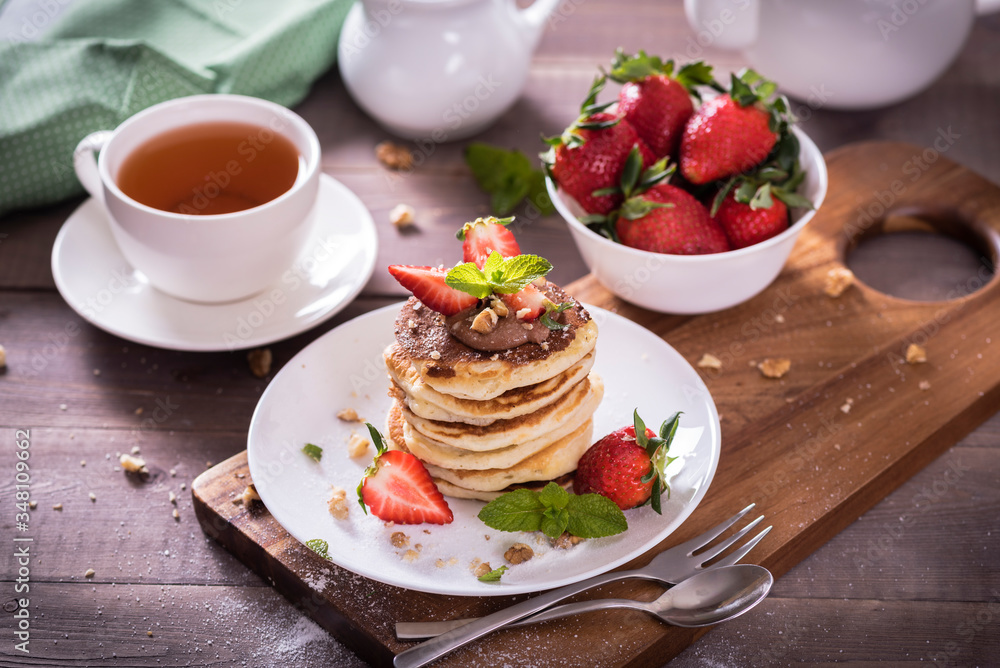 Pancakes  with chocolate sauce and fresh  strawberries on brawn wooden background. Delicious sweet dessert.