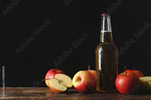 Fototapeta Naklejka Na Ścianę i Meble -  Composition with cider and apples on wooden table against black background