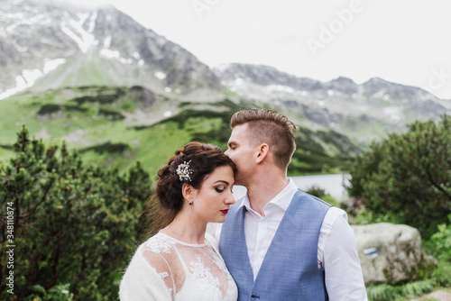 Beautiful bride and groom hug and kiss in the mountains. Wedding photo session in the mountains. © Oksana