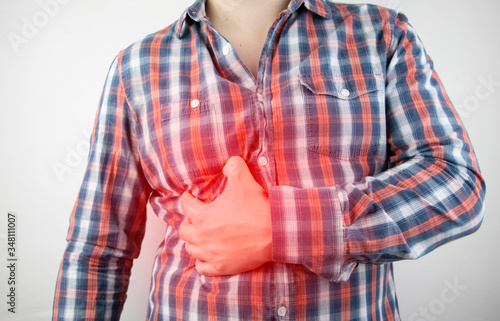 A man grabs his right side under the ribs. Pain in the liver. Pain syndrome in liver disease.