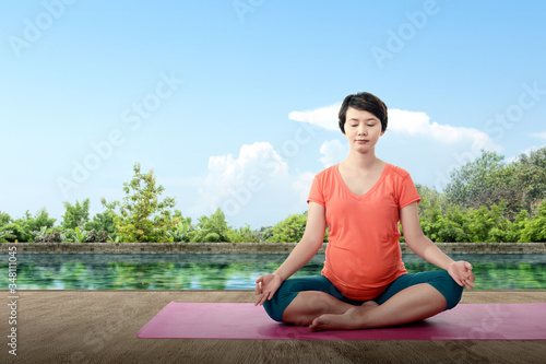 Asian pregnant woman is practicing yoga in yoga mat