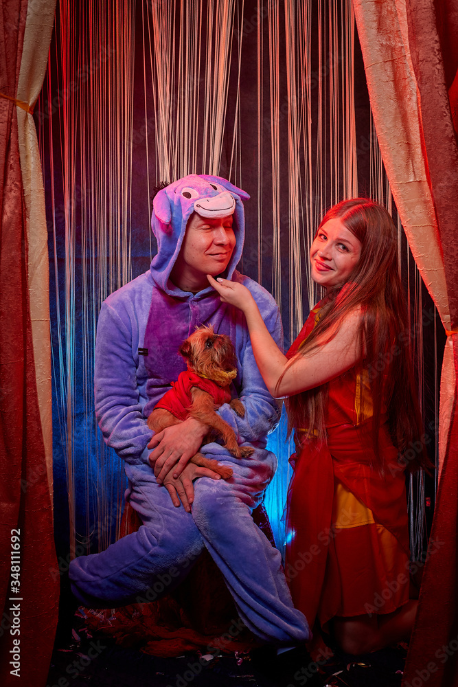 Man and woman with small dor on the theater stage. Photo shoot in the circus style with girl, boy and pet