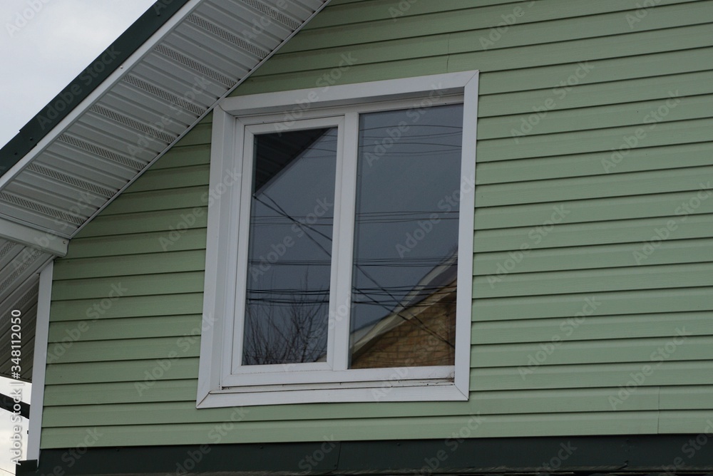attic of a private house with a green plastic wall and one white window on the street attic of a private house with a green plastic wall and one white window on the street