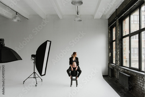 Beautiful pregnant woman in underwear and a black suit in the studio.