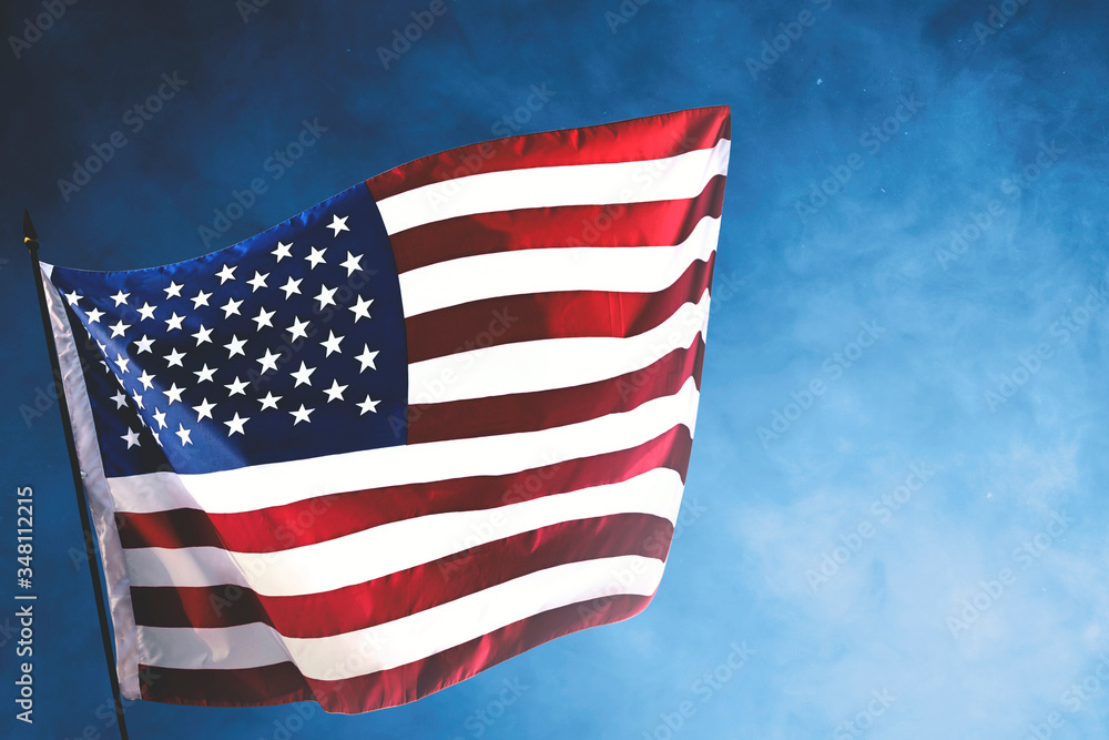 Fototapeta premium American flag waving in the air with a blue background
