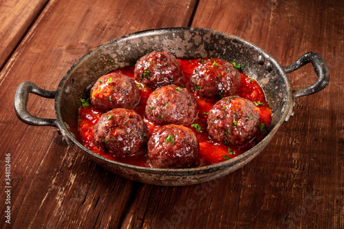 Meatballs with tomato sauce, a close-up in a pan on a dark rustic wooden background