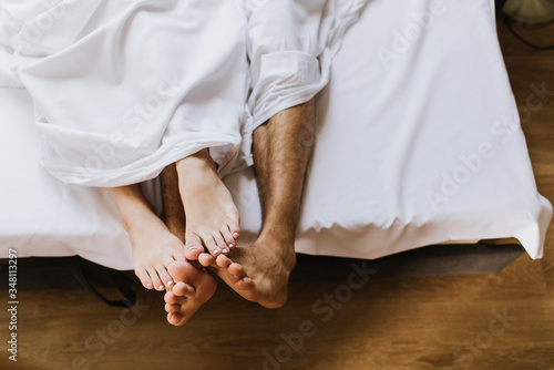 Legs of man and woman in bed.