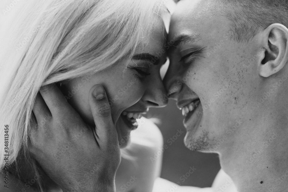 Young man and woman in sheets hug, kiss and laugh. Black and white photo of naked men and women in sheets. Young man and woman in sheets hug, kiss and laugh. Black and white photo of naked men and women in sheets.