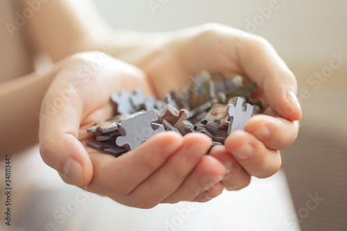Mixed jigsaw puzzle pieces in hands, macro close up. Problem solving concept