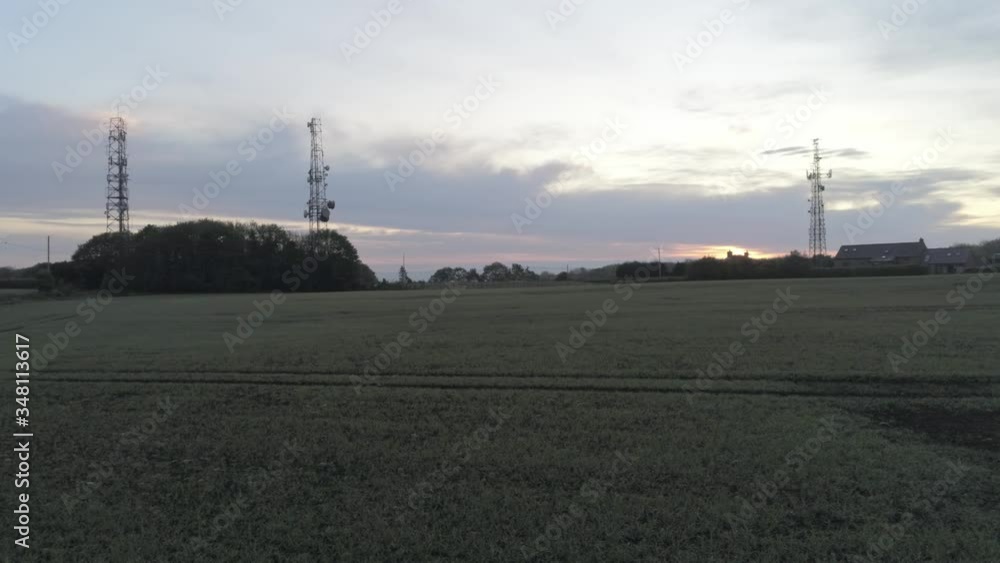 Sunrise telecom towers dolly right low aerial view on agricultural farmland at dawn Sunrise telecom towers dolly right low aerial view on agricultural farmland at dawn