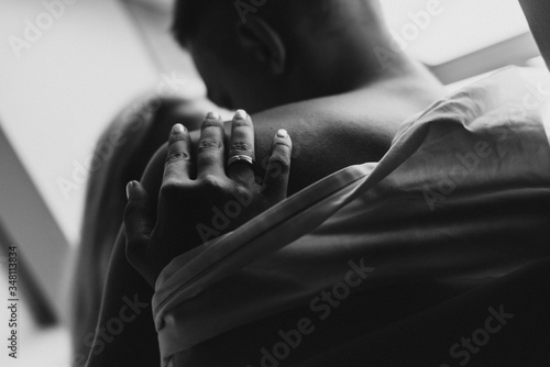 Young man and woman in sheets hug and kiss near the window. Black and white photo of a naked man and woman by the window.