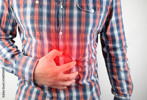 A man holds on to his stomach. Pain in the abdominal cavity. The concept of diseases of the stomach and digestive system. photo