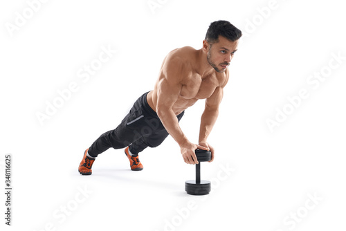 Muscular man doing push ups using dumbbell.