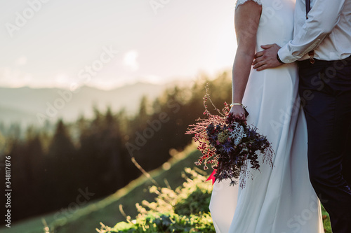 Brautpaar mit Brautstrauß in den Bergen in Österreich
